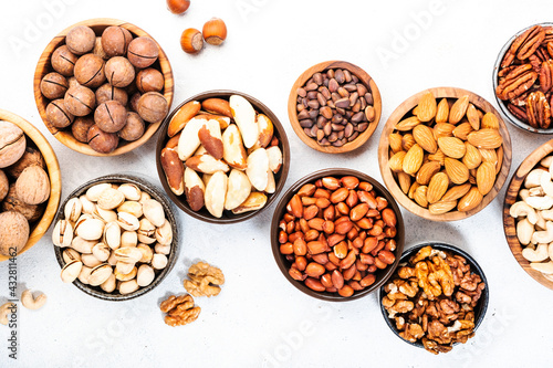 Nuts in bowls set. Cashews, hazelnuts, walnuts, pistachios etc. Healthy food snack mix on white table, top view
