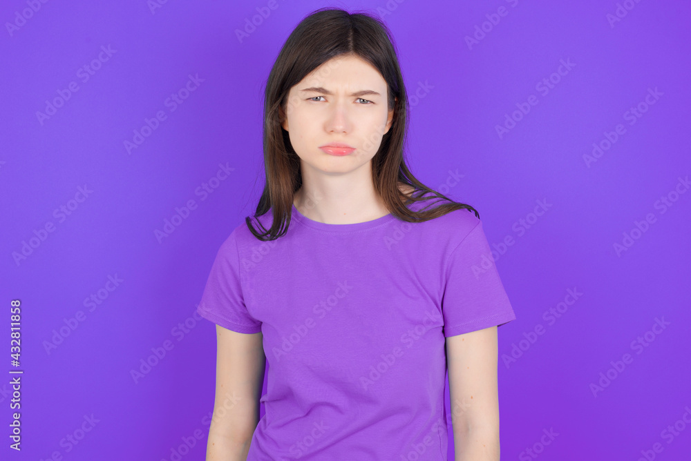 Fototapeta premium young beautiful Caucasian girl wearing purple T-shirt over purple background depressed and worry for distress, crying angry and afraid. Sad expression.