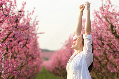 Konstfotografi Excited woman raising arms celebrating spring in a field