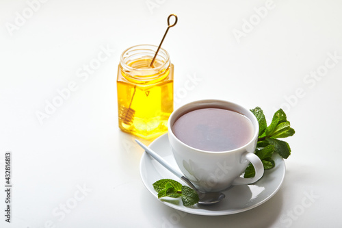 Black tea in white cup with mint leaves and honey. Calming and revitalizing tea, anti-stress and relaxation