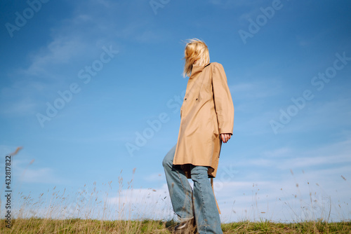 Portrait of young woman  is standing on the meadow, enjoys a spring sunny day outdoors. People, lifestyle, travel, nature and vacations concept. © maxbelchenko