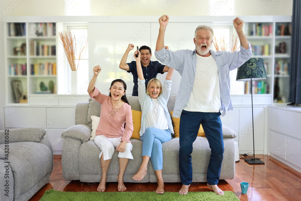 Excited and surprised multiethnic senior people in in casual dress sitting in living room, watching TV television and screaming shocked with good news. Four friendly mixed race having fun with smiling Excited and surprised multiethnic senior people in in casual dress sitting in living room, watching TV television and screaming shocked with good news. Four friendly mixed race having fun with smiling