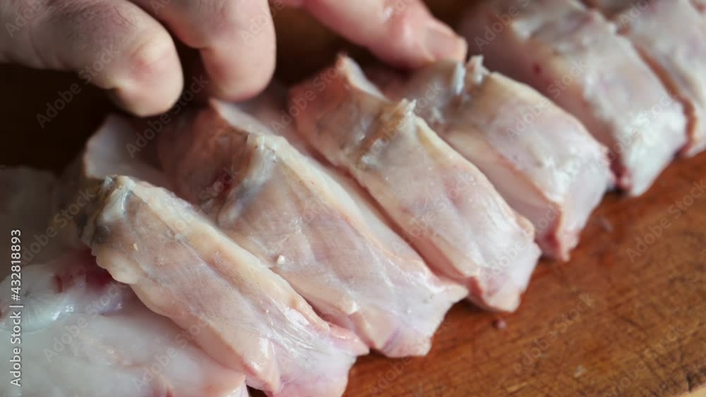 Close up shot of slices of monkfish arranged on a cutting board. One hand touches and checks the slices. Mediterranean diet, food and health concept. Close up shot of slices of monkfish arranged on a cutting board. One hand touches and checks the slices. Mediterranean diet, food and health concept.