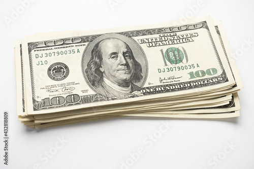 A money pile of stacked one hundred US banknotes with president Franklin portrait on white background. Cash of hundred dollar bills, paper money currency.