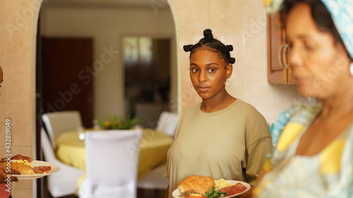 Young girl holding plate of food in kitchen