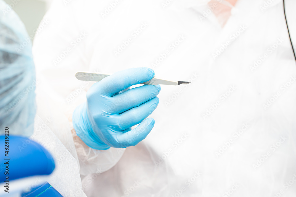 scalpel in the hands of the dentist. dental implantation surgery. scalpel in the hands of the dentist. dental implantation surgery.