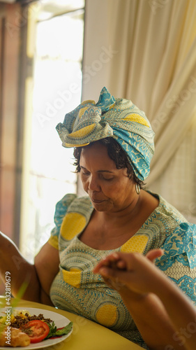 Elderly woman praying at breakfast table