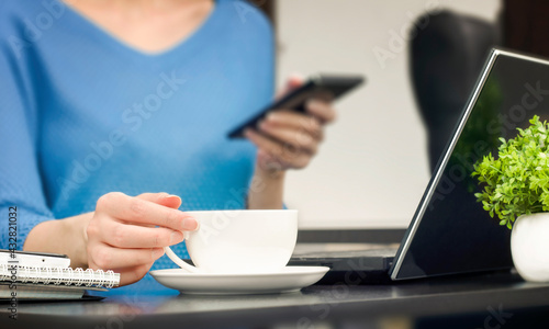 woman sitting at the table works and drinks coffee. freelance concept