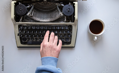 Woman's hand typing on a vintage typewriter top view.