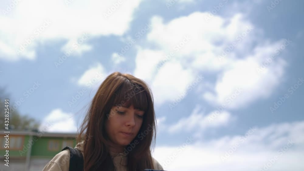 A young pretty woman records a voice message on her smartphone. In the background, the seashore. Tilt shot and distance. The concept of modern communication. A young pretty woman records a voice message on her smartphone. In the background, the seashore. Tilt shot and distance. The concept of modern communication.
