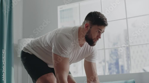 Bearded athlete man in t-shirt practices bent-over rows photo