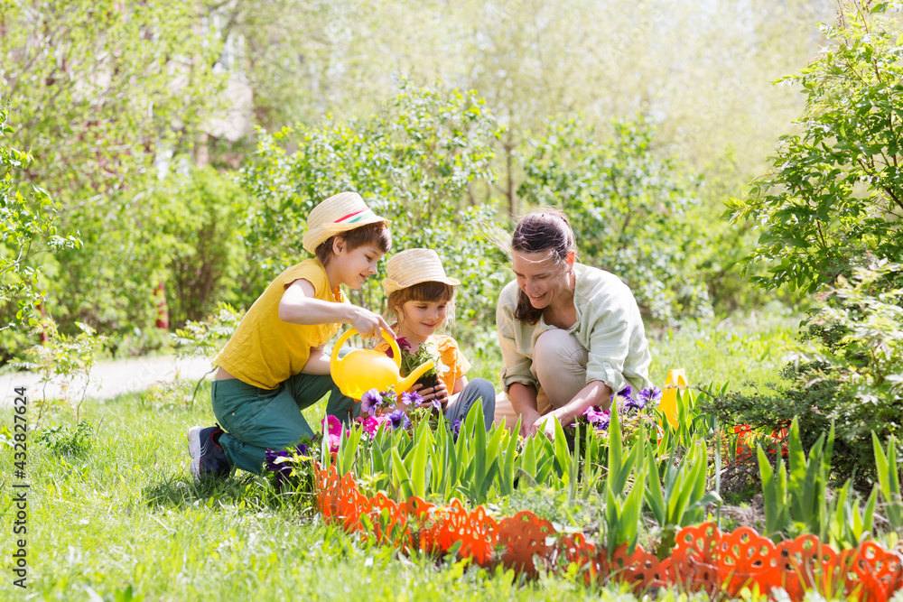 mother and two kids plant flowers in the garden near the houme on