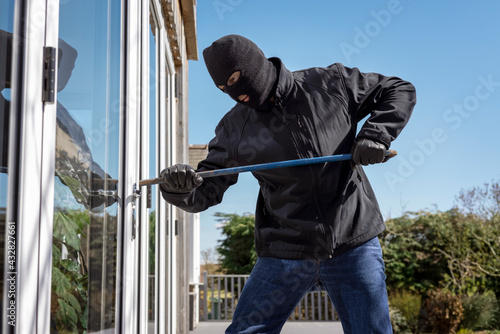Fotografiet Burglar breaking into a house via a window with a crowbar