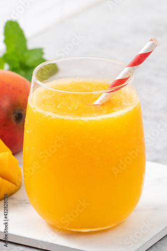 Fresh beautiful delicious mango juice smoothie in a glass cup on gray table background.