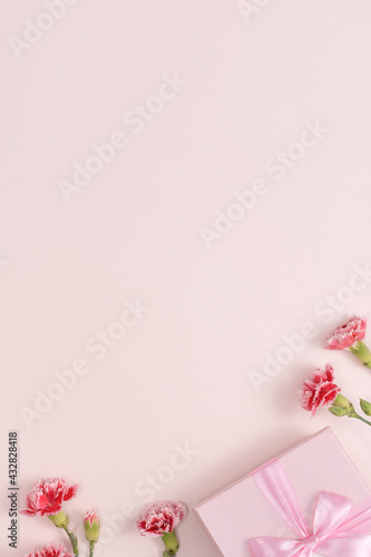 Mother's day background. Top view of gift with carnation bouquet on pink table background