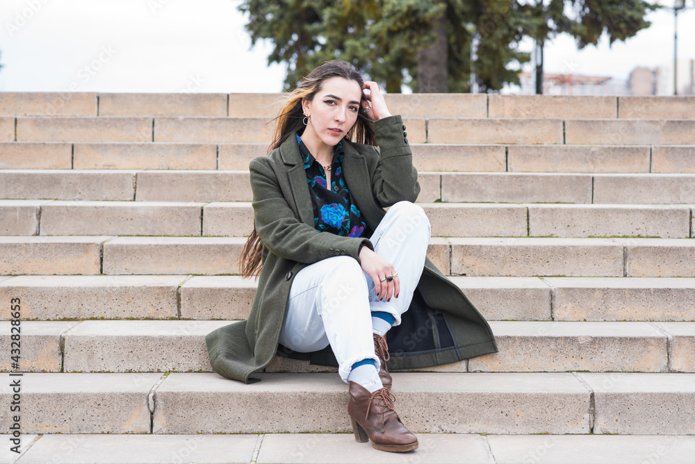Portrait of a beautiful and pensive hippie girl who sits on the steps