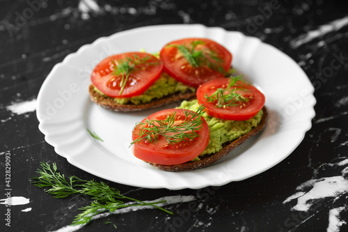Sandwiches with grated fresh avocado and tomato slices on a white plate. Healthy eating. High quality photo