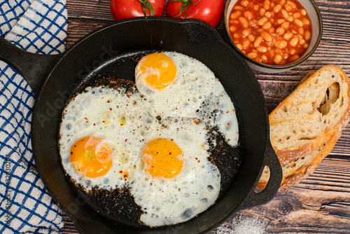 English breakfast, fried eggs and baked beans with grilled bread