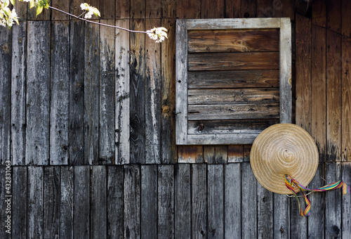 Straw hat hanging on the wooden country house wall, exterior