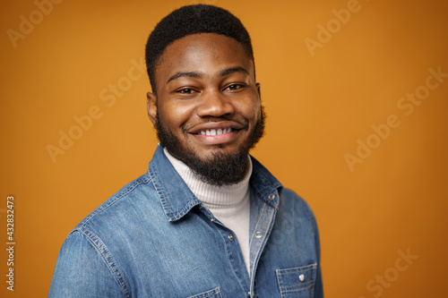 Portrait of young handsome african american guy against yellow background