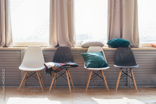 Home interior. Chairs arranged in a row under window.