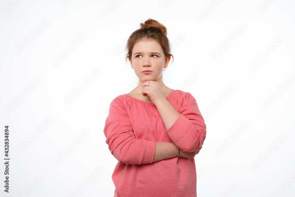 Young girl with thoughtful expression, keeps hand on chin, plans something or makes choice. Studio shot white background Young girl with thoughtful expression, keeps hand on chin, plans something or makes choice. Studio shot white background