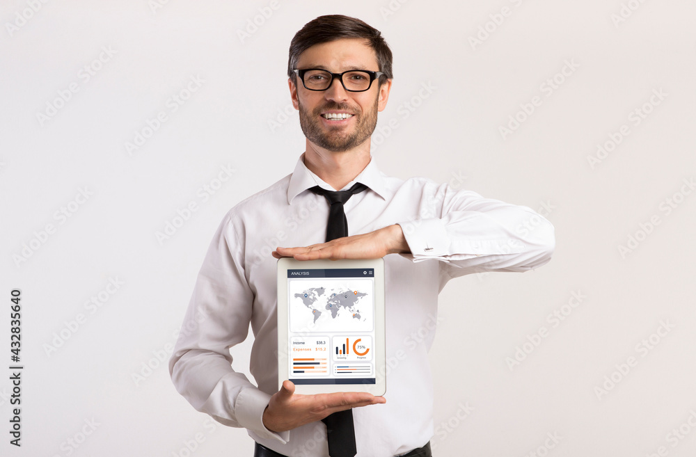 Cheerful entrepreneur holding digital tablet with financial app on screen Cheerful entrepreneur holding digital tablet with financial app on screen