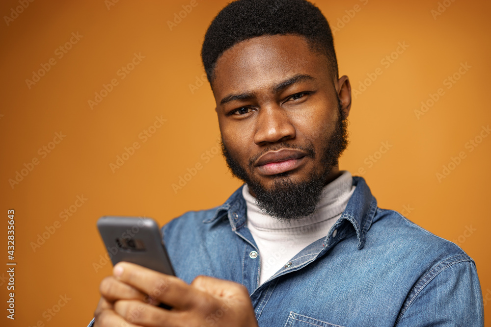 Portrait of young african american man using his smartphone against yellow background Portrait of young african american man using his smartphone against yellow background