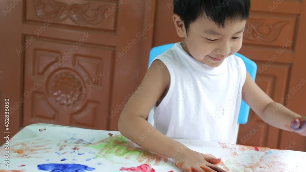 4K Asian child boy showing color hands and fingers, painting on paper with happy smile at home. Cute kid playing watercolor with happy moment. Concept of art, family fun activity, creative learning. 4K Asian child boy showing color hands and fingers, painting on paper with happy smile at home. Cute kid playing watercolor with happy moment. Concept of art, family fun activity, creative learning.