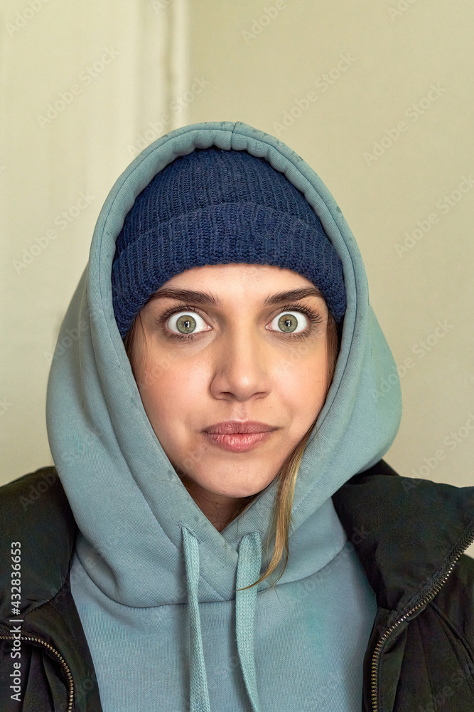 Young beautiful girl with big eyes looking at camera in a sweatshirt with a hood Young beautiful girl with big eyes looking at camera in a sweatshirt with a hood
