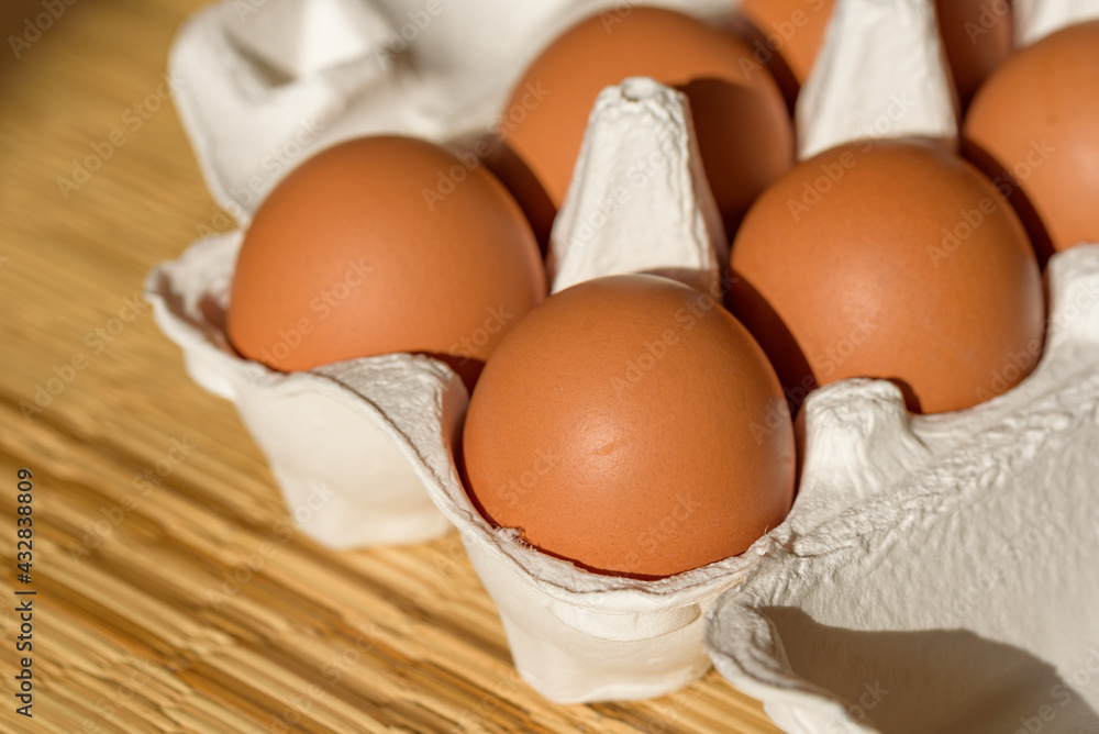 Chicken eggs in a paper carton, straw mat background Chicken eggs in a paper carton, straw mat background