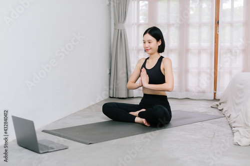 Asian young sporty slim woman coach internet video online training oga instructor modern laptop screen meditate relax breathe easy seat pose gym healthy lifestyle concept.