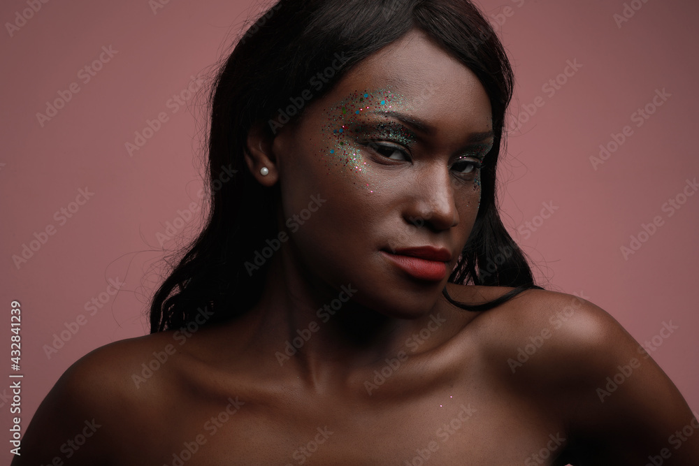 Portrait of young black woman posing in the studio, with glittery make-up.