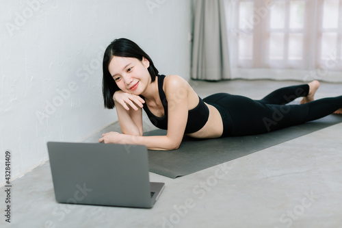 Girl training at home, exercising and watching videos on laptop, training in living room