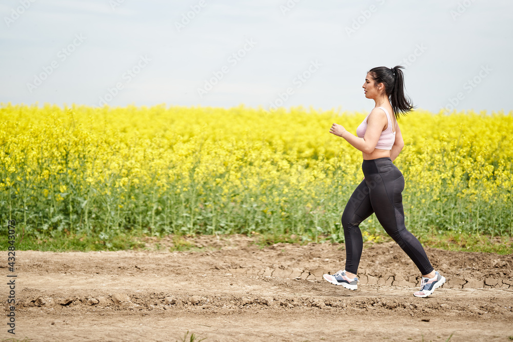 Plus size woman running on a countryside dirt road Plus size woman running on a countryside dirt road