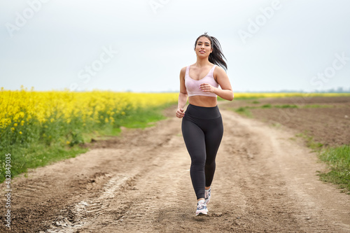 Plus size woman running on a countryside dirt road