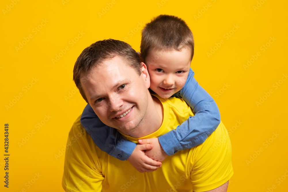 Happy father's day! Emotional dad and son hugging on yellow background. Happy father's day! Emotional dad and son hugging on yellow background.