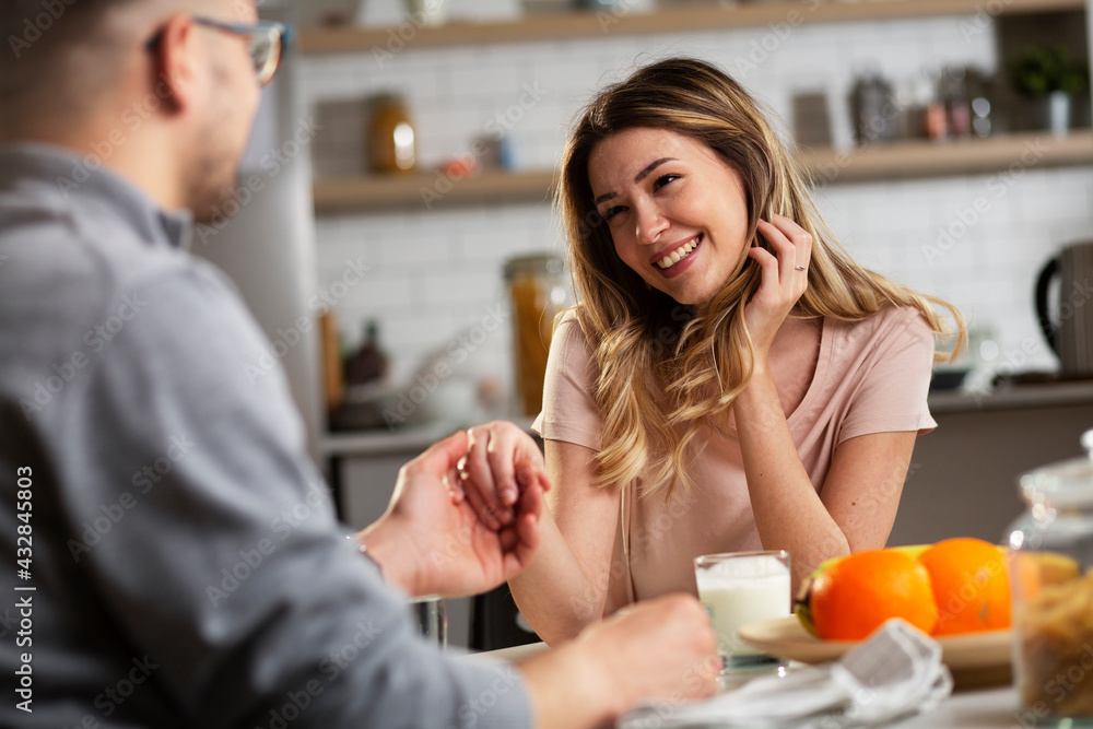 Beautiful young girl enjoying in breakfast with her boyfriend. Loving couple drinking coffee in the kitchen.. Beautiful young girl enjoying in breakfast with her boyfriend. Loving couple drinking coffee in the kitchen..