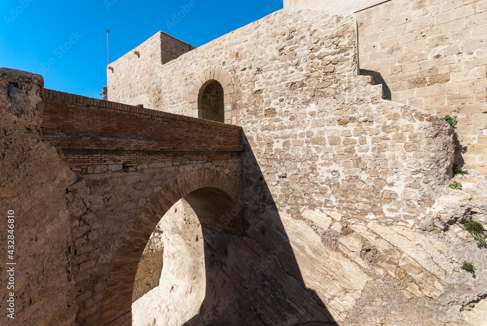 Santa Barbara castle in Alicante, view of the old stone walls and the stone arch bridge with the entrance to the next level of the castle.