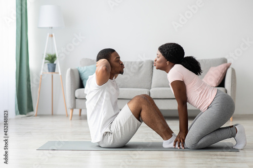 Sporty black man and woman exercising together at home