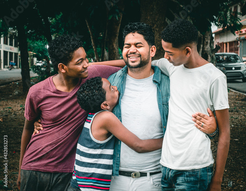 Dominican Latino origin man celebrating father's day with his children , in the park, dark-skinned family having fun, children hugging their father photo