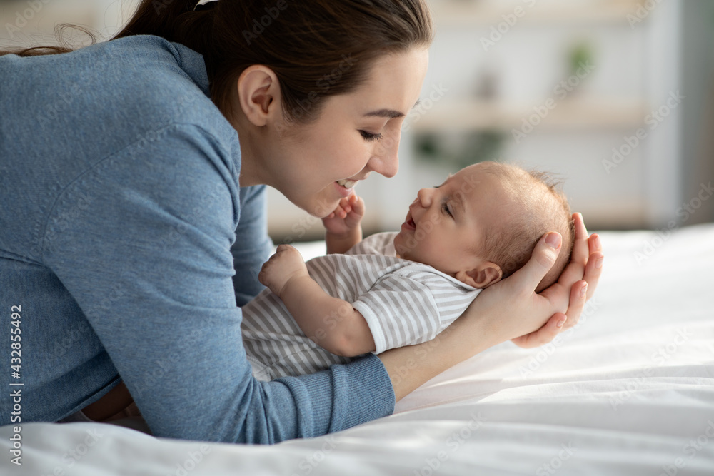 Joy Of Motherhood. Happy Young Mom Relaxing In Bed With Newborn Baby Joy Of Motherhood. Happy Young Mom Relaxing In Bed With Newborn Baby
