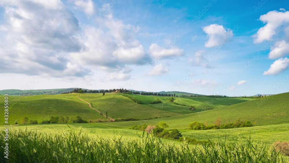 Time lapse: unique green landscape in Volterra region, Tuscany, Italy. Scenic clouds moving by wind. Sunset light over cultivated hill range and cereal crop fields. Time lapse: unique green landscape in Volterra region, Tuscany, Italy. Scenic clouds moving by wind. Sunset light over cultivated hill range and cereal crop fields.