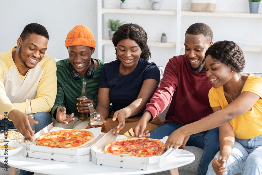 Happy african american friends eating pizza at home