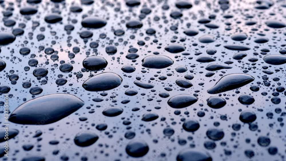 Raindrops falling on a gray plate reflected on the sky and clouds, the pattern of raindrops on a gray metal. Raindrops falling on a gray plate reflected on the sky and clouds, the pattern of raindrops on a gray metal.