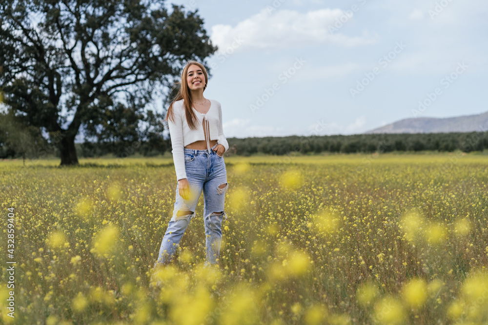 Young woman posing happily in a field of yellow flowers Young woman posing happily in a field of yellow flowers
