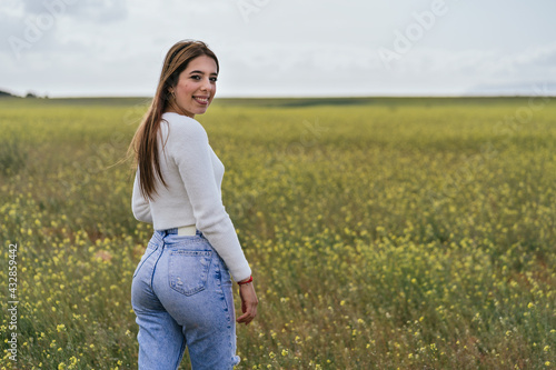 Young woman posing happily in a field of yellow flowers