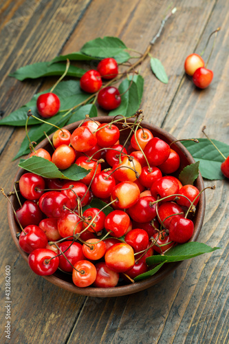 Fresh cherries with leaves in a clay bowl
