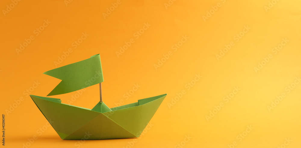 Green paper boat on a yellow background with space for your text Green paper boat on a yellow background with space for your text