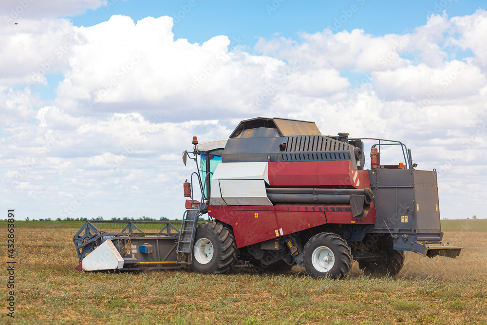 A large combine works in a wheat field A large combine works in a wheat field